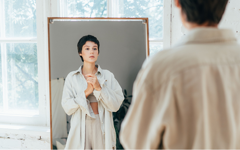 Instante íntimo de una mujer reconociéndose frente al espejo, símbolo de aceptación corporal