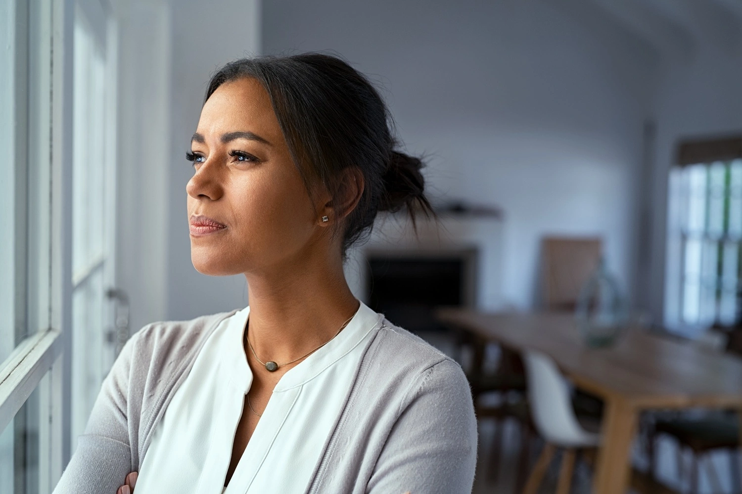 Mujer reflexiva mirando por la ventana, símbolo de desconexión emocional femenina.